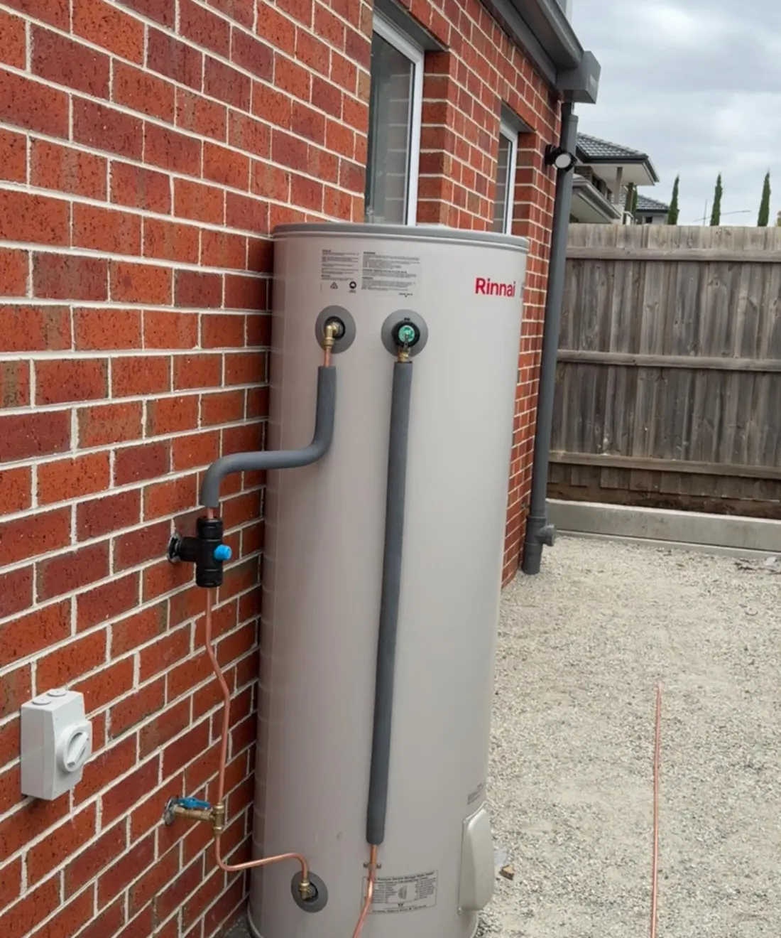 Storage hot water unit against a brick wall with insulated copper connections